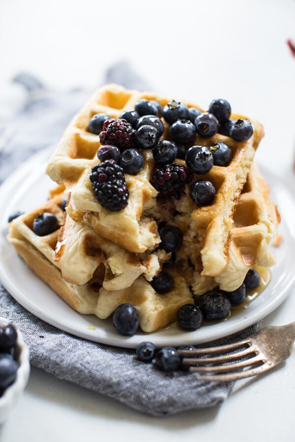 Stack of Belgian waffles on white background with berries and fork