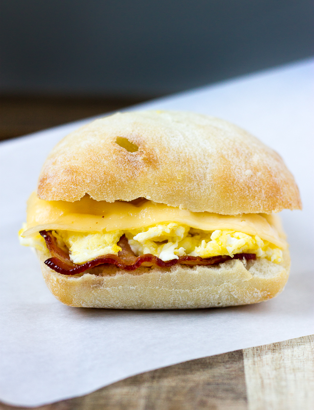 close up of breakfast sandwich with bacon, egg, and gouda cheese on ciabatta roll