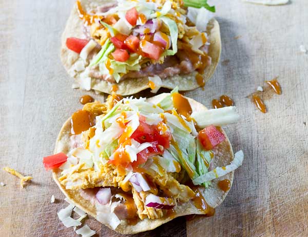 Slow Cooker BBQ Chicken Tostadas-- pulled chicken breast cooked with Trader Joe's famous Carolina Gold BBQ Sauce topped on crispy baked tostadas and veggies. This weeknight dinner will quickly become a family favorite. High protein and gluten-free.| @KristinaLaRueRD | loveandzest.com