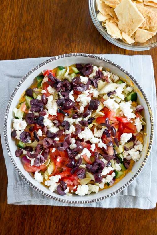 This Greek 7 Layer Dip is loaded with only the good stuff-- roasted red pepper hummus and loads of veggies. Perfect appetizer to serve at any party. 