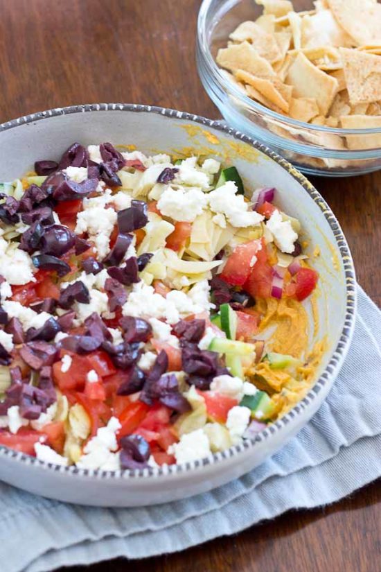 This Greek 7 Layer Dip is loaded with only the good stuff-- roasted red pepper hummus and loads of veggies. Perfect appetizer to serve at any party. 