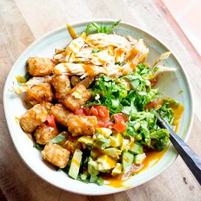 Comfort food meets salad greens. Get obsessed over this salad combo... crispy take-me-back-to-my-childhood tater tots, warm grilled chicken and crunchy shredded greens all smothered in BBQ sauce for the win!