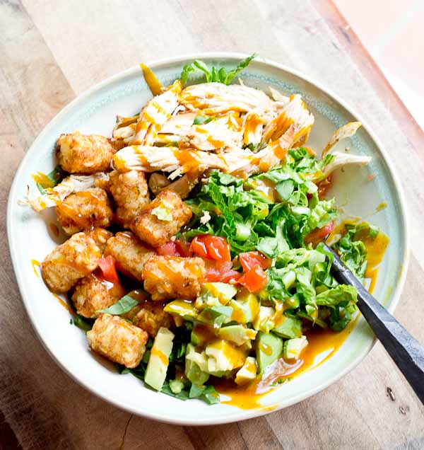 Comfort food meets salad greens. Get obsessed over this salad combo... crispy take-me-back-to-my-childhood tater tots, warm grilled chicken and crunchy shredded greens all smothered in BBQ sauce for the win! 