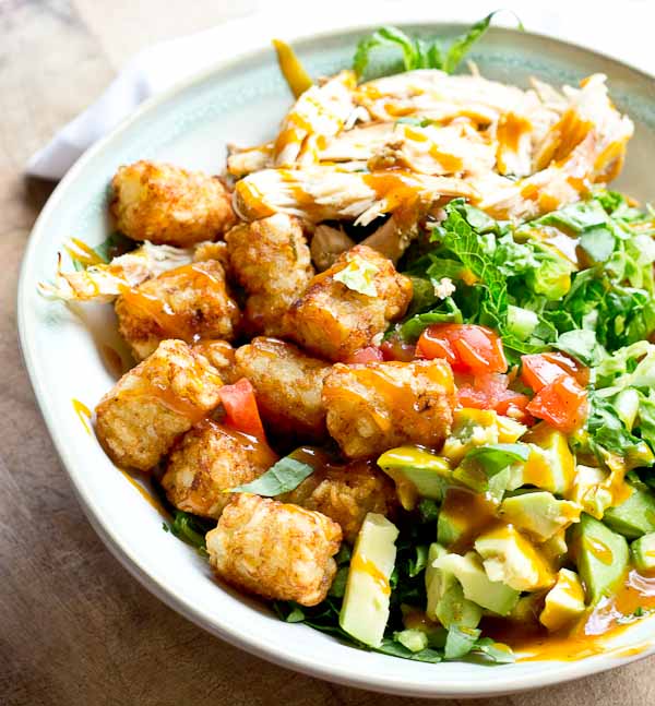 Comfort food meets salad greens. Get obsessed over this salad combo... crispy take-me-back-to-my-childhood tater tots, warm grilled chicken and crunchy shredded greens all smothered in BBQ sauce for the win! 