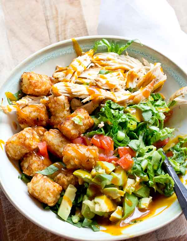 Comfort food meets salad greens. Get obsessed over this salad combo... crispy take-me-back-to-my-childhood tater tots, warm grilled chicken and crunchy shredded greens all smothered in BBQ sauce for the win! 