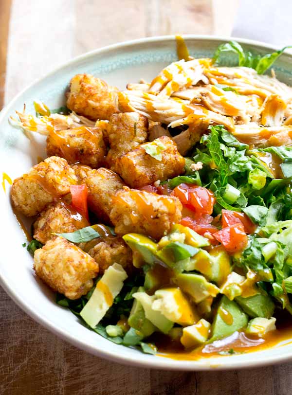 Comfort food meets salad greens. Get obsessed over this salad combo... crispy take-me-back-to-my-childhood tater tots, warm grilled chicken and crunchy shredded greens all smothered in BBQ sauce for the win! 