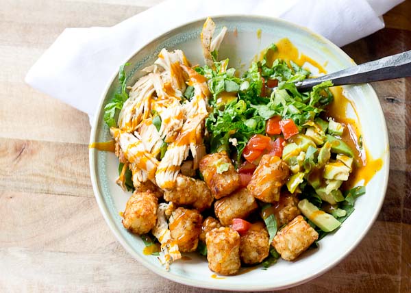 Comfort food meets salad greens. Get obsessed over this salad combo... crispy take-me-back-to-my-childhood tater tots, warm grilled chicken and crunchy shredded greens all smothered in BBQ sauce for the win! 