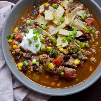 This Turkey Taco Soup is easy peasy to make for a weeknight dinner... a healthy meal the whole family will enjoy. Toss all ingredients into a pot and simmer until you're ready to eat! The toppings are the best part! | @KristinaLaRueRD | www.loveandzest.com