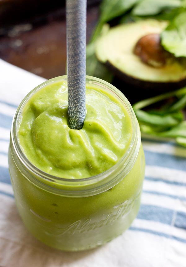close up shot of creamy avocado green smoothie with straw