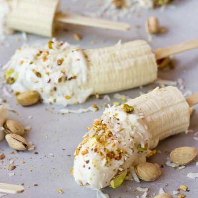 These Banana Crunch Pops are just what you need on a hot summer day, kids and adults rejoice! Only 5 ingredients and very simple to make! Place banana on stick, dunk in Greek yogurt and roll in pistachios and shredded coconut and freeze.