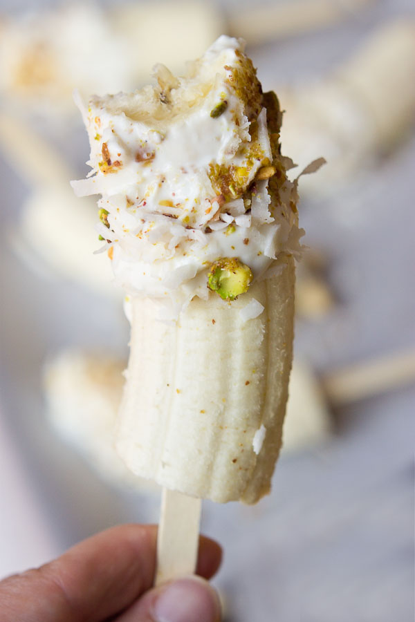  These Banana Crunch Pops are just what you need on a hot summer day, kids and adults rejoice! Only 4 ingredients and very simple to make! Place banana on stick, dunk in Greek yogurt and roll in pistachios and shredded coconut and freeze.