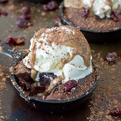 Double Chocolate Cherry Skillet Brownies a la mode with vanilla ice cream, almond butter drizzle, and chocolate shavings. This skillet brownie is lower in sugar and made with healthier ingredients like almond butter, whole grains, dried Montmorency tart cherries, and dark chocolate.