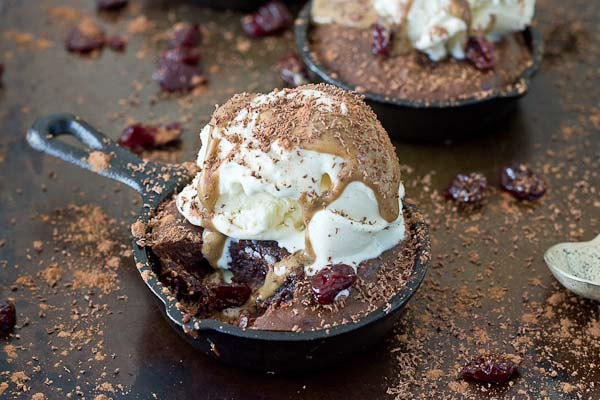 Double Chocolate Cherry Skillet Brownies a la mode with vanilla ice cream, almond butter drizzle, and chocolate shavings. This skillet brownie is lower in sugar and made with healthier ingredients like almond butter, whole grains, dried Montmorency tart cherries, and dark chocolate. 