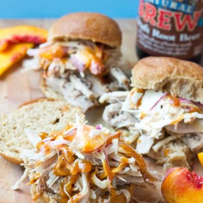 Root Beer Pulled Pork with Peach Slaw made in the slow cooker just in time for game day! This recipe has a simple ingredient list and that Homemade BBQ Sauce and those peaches in that Peach Slaw, you can't miss out on that sweetness. YUM!