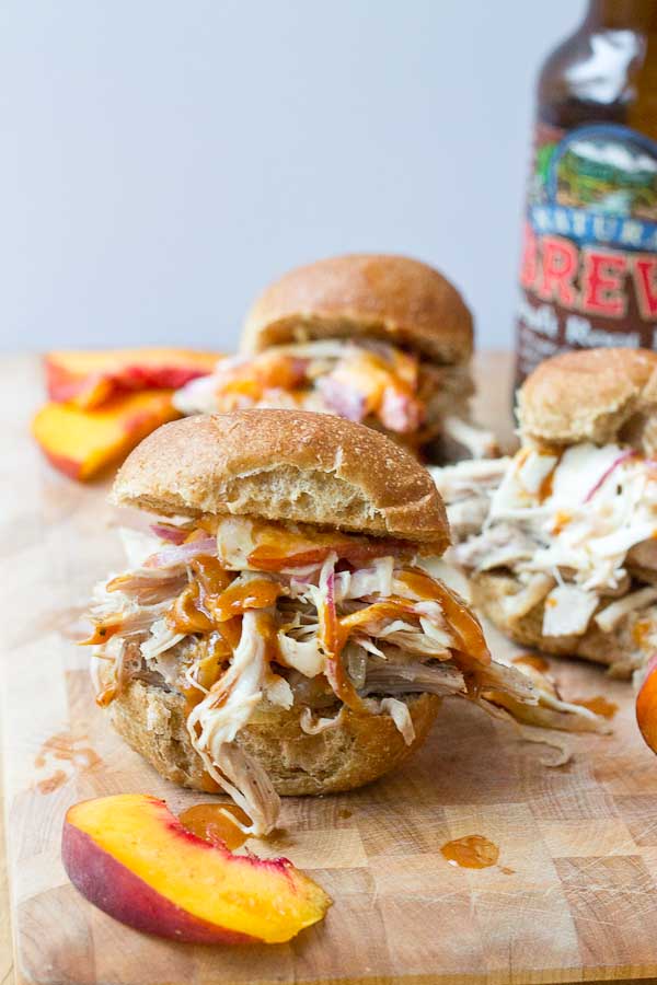 Root Beer Pulled Pork with Peach Slaw made in the slow cooker just in time for game day! This recipe has a simple ingredient list and that Homemade BBQ Sauce and those peaches in that Peach Slaw, you can't miss out on that sweetness. YUM!