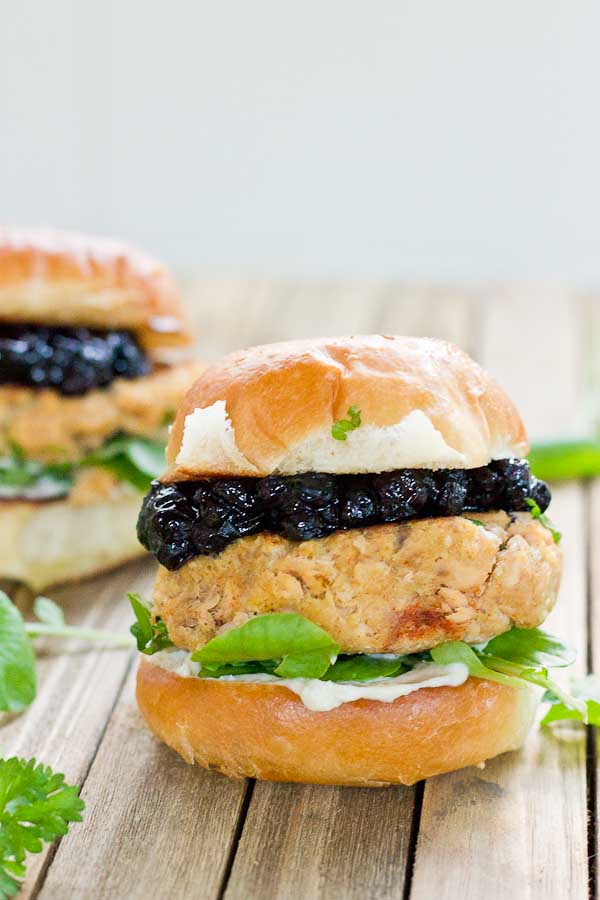 These Salmon Sliders with Blueberry Compote are quite possibly the best way to eat salmon at home! Convenience, price, and deliciousness! Warm salmon cakes, wild blueberries compote, maple goat cheese spread, toasted buttery buns = BEST FOOD EVER.