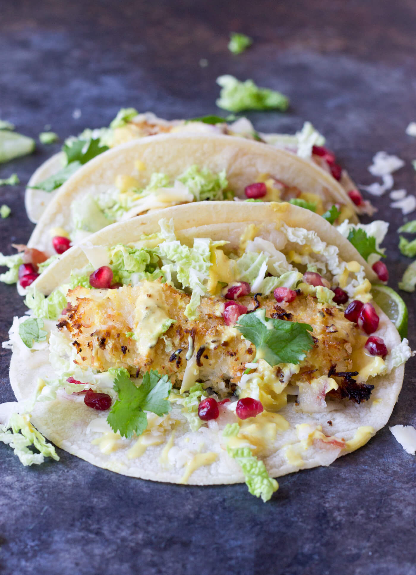 Crazy for tacos? Add these Crispy Fish Tacos to your menu! Crispy baked cod topped with pomegranates, shredded pear, and Honey Lime Crema. Simple to make at home!