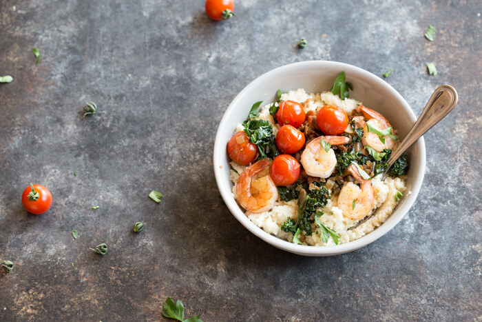 Shrimp and Cheesy Cauliflower Grits, a low carb southern breakfast. Cheesy cauliflower grits topped with savory shrimp, bacon, a hearty dose of kale, and blistered cherry tomatoes. 