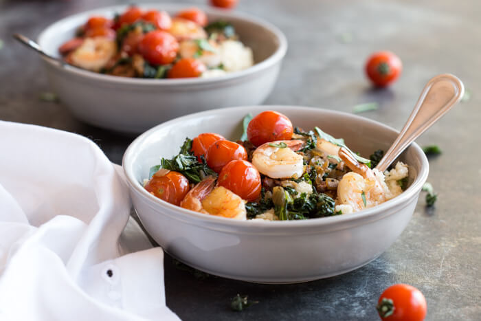 Shrimp and Cheesy Cauliflower Grits, a low carb southern breakfast. Cheesy cauliflower grits topped with savory shrimp, bacon, a hearty dose of kale, and blistered cherry tomatoes. 