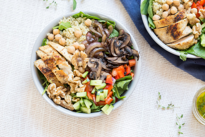 The perfect summer salad has grilled ingredients served warm served with fresh raw veggies. This Mediterranean Quinoa Chicken Salad bowl is topped with grilled chicken, sautéed onions and mushrooms and a zesty herb dressing.