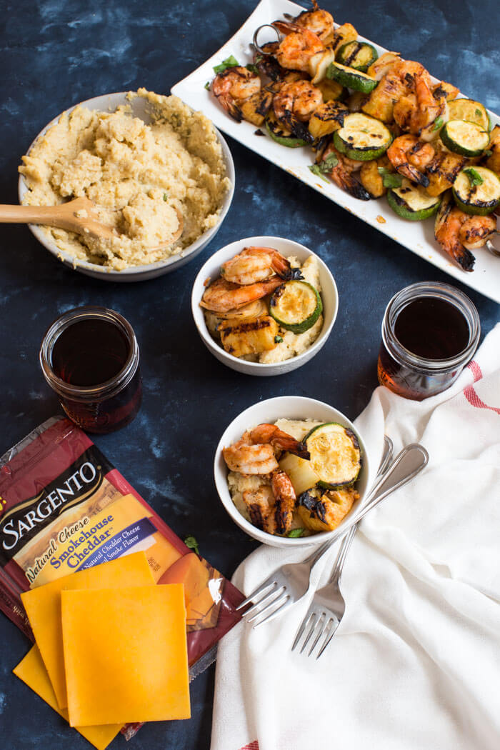 A classic southern dish gets a smoky twist with these Smoky Cheddar Cauliflower Grits and Cajun Shrimp. Cheesy cauliflower grits are served alongside sweet and spicy shrimp skewers with zucchini and pineapple.