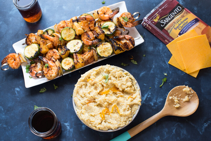 A classic southern dish gets a smoky twist with these Smoky Cheddar Cauliflower Grits and Cajun Shrimp. Cheesy cauliflower grits are served alongside sweet and spicy shrimp skewers with zucchini and pineapple.