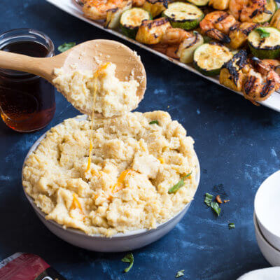 A classic southern dish gets a smoky twist with these Smokehouse Cheddar Cauliflower Grits and Cajun Shrimp. Cheesy cauliflower grits are served alongside sweet and spicy shrimp skewers with zucchini and pineapple.