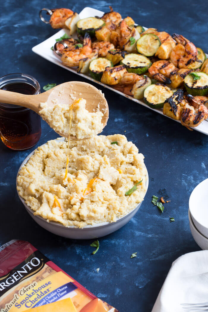 A classic southern dish gets a smoky twist with these Smoky Cheddar Cauliflower Grits and Cajun Shrimp. Cheesy cauliflower grits are served alongside sweet and spicy shrimp skewers with zucchini and pineapple.