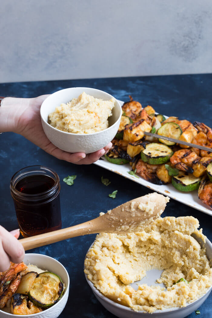 A classic southern dish gets a smoky twist with these Smoky Cheddar Cauliflower Grits and Cajun Shrimp. Cheesy cauliflower grits are served alongside sweet and spicy shrimp skewers with zucchini and pineapple.