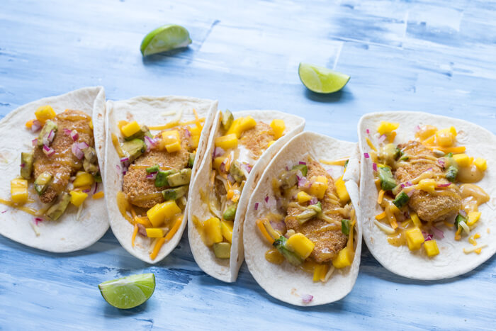 Honey Mustard Fish Tacos made with wild caught pollock tenders, onion, mango, avocado, and cheese nestled in a tortilla and drizzled with honey mustard! A tasty dinner on the table in less than 20 minutes.