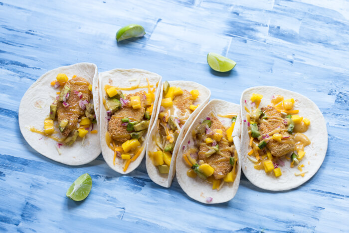 Honey Mustard Fish Tacos made with wild caught pollock tenders, onion, mango, avocado, and cheese nestled in a tortilla and drizzled with honey mustard! A tasty dinner on the table in less than 20 minutes.