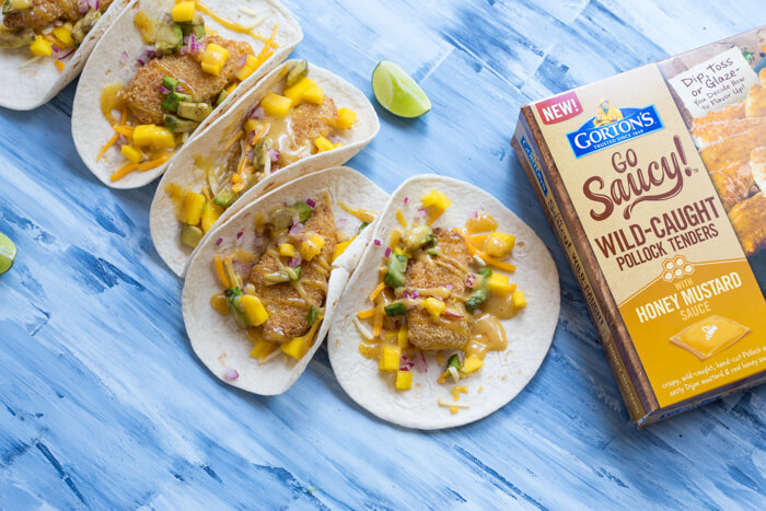 Honey Mustard Fish Tacos made with wild caught pollock tenders, onion, mango, avocado, and cheese nestled in a tortilla and drizzled with honey mustard! A tasty dinner on the table in less than 20 minutes.