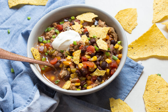 overhead shot of turkey taco soup with crushed tortilla chips and sour cream 