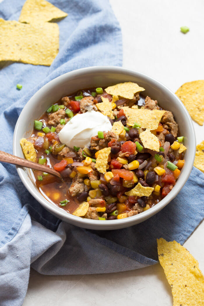 overhead shot of turkey taco soup with crushed tortilla chips and sour cream 