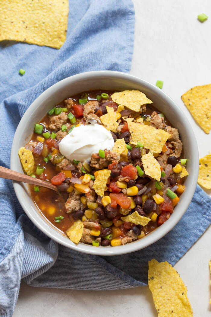 overhead shot of turkey taco soup with crushed tortilla chips and sour cream 