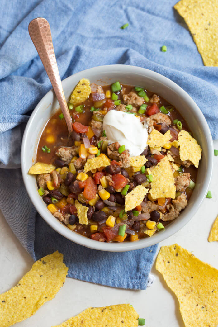 overhead shot of turkey taco soup with crushed tortilla chips and sour cream 