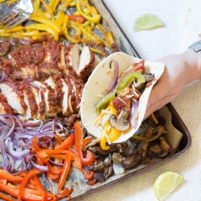 Sheet Pan Chicken Fajitas are our new weeknight dinner wonder. Check it, all the fajita veg plus super moist flavor packed chicken loaded on one pan and baked in the oven... then wrapped in soft tortillas and topped with cheddar, sour cream and avocado. What's not to love?