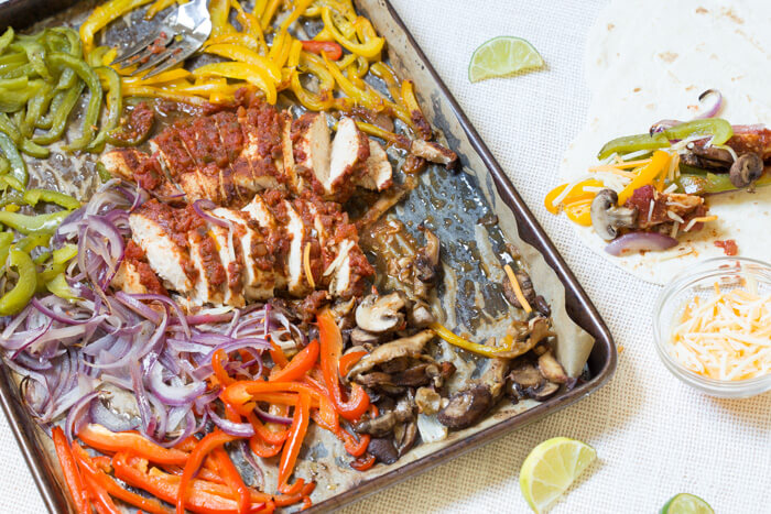 Sheet Pan Chicken Fajitas are our new weeknight dinner wonder. Check it, all the fajita veg plus super moist flavor packed chicken loaded on one pan and baked in the oven... then wrapped in soft tortillas and topped with cheddar, sour cream and avocado. What's not to love?