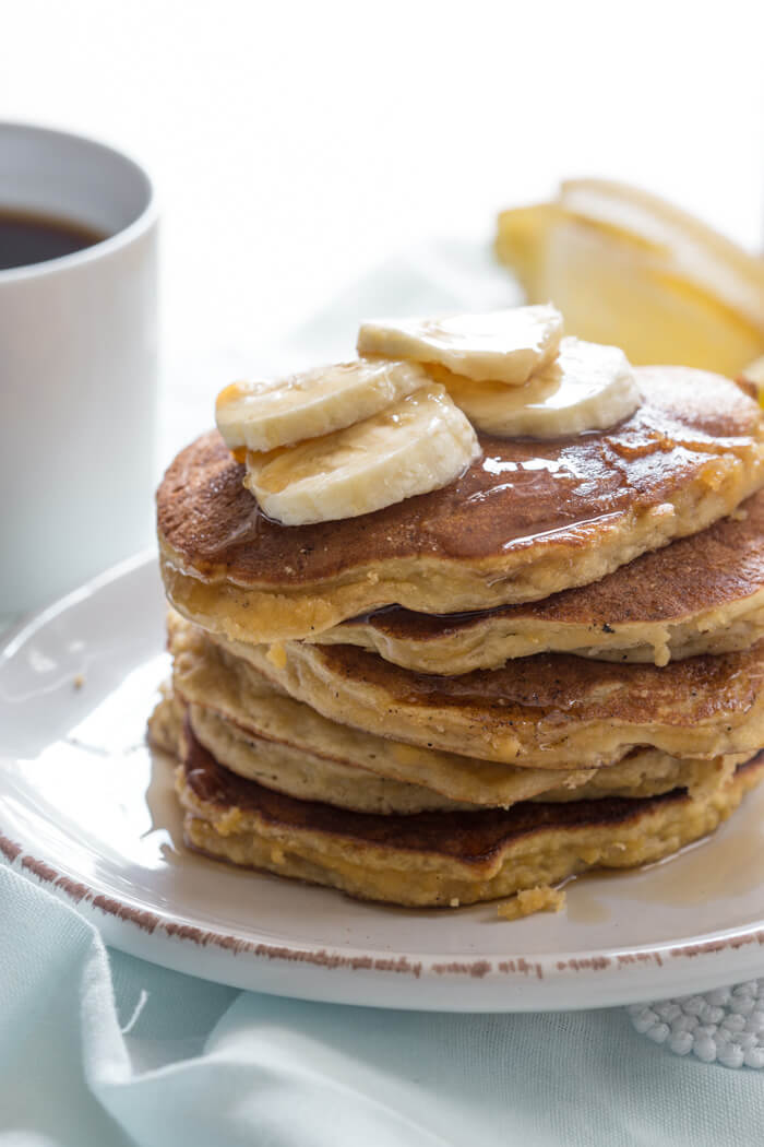 side shot of paleo banana coconut flour pancake with sliced bananas and maple syrup 