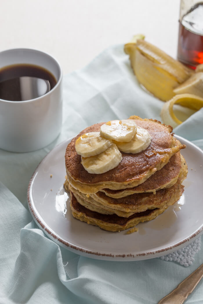 overhead shot of paleo banana coconut flour pancakes with sliced bananas and maple syrup