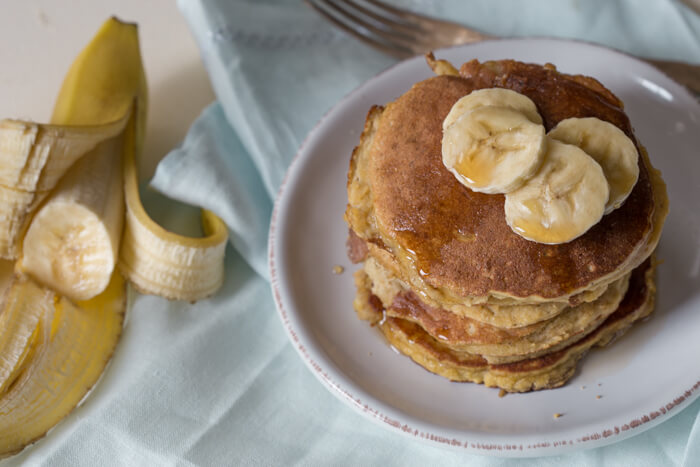 overhead shot of paleo banana coconut flour pancakes with sliced bananas and maple syrup