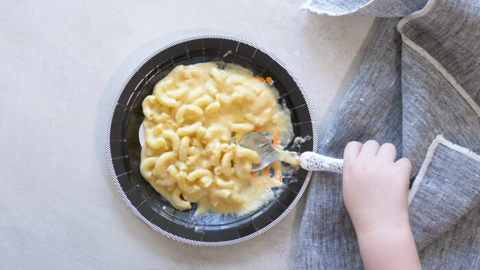 toddler hand eating pumpkin mac n cheese