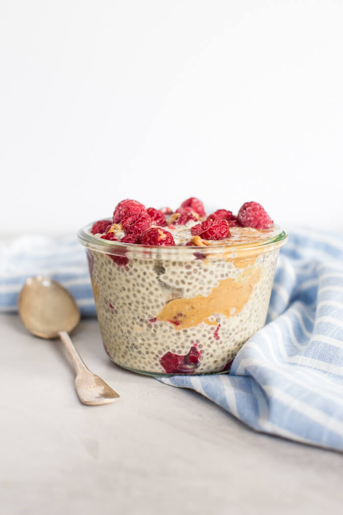 Side shot of PB&J Chia pudding topped with fresh raspberries and drizzled with peanut butter