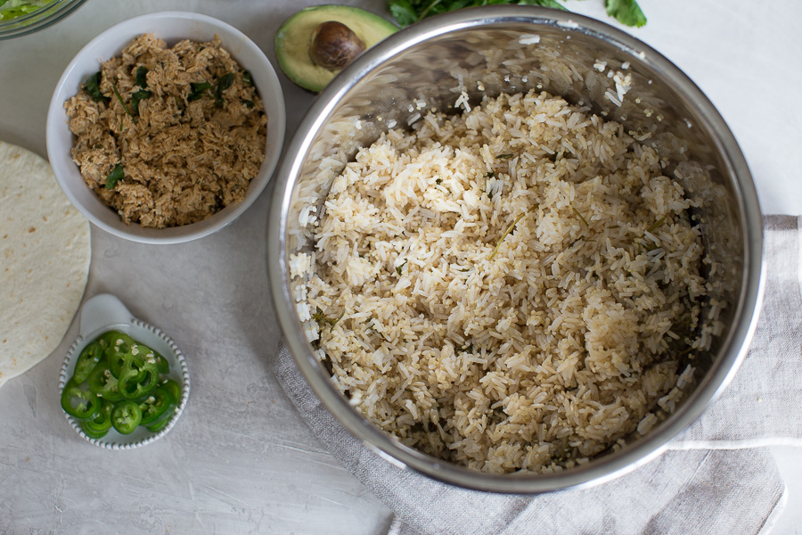 Overhead shot of cilantro lime rice in the Instant Pot with side of fresh jalapenos, shredded chicken, flour tortilla and avocado 