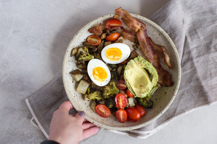 soft boiled eggs in ceramic bowl with avocado, bacon, potatoes and tomatoes