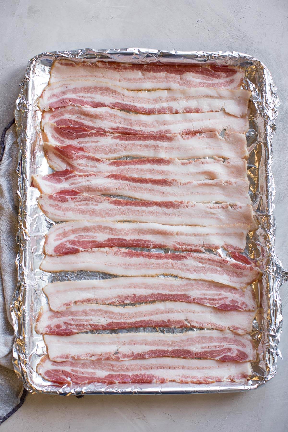 uncooked bacon on baking sheet about to go in oven