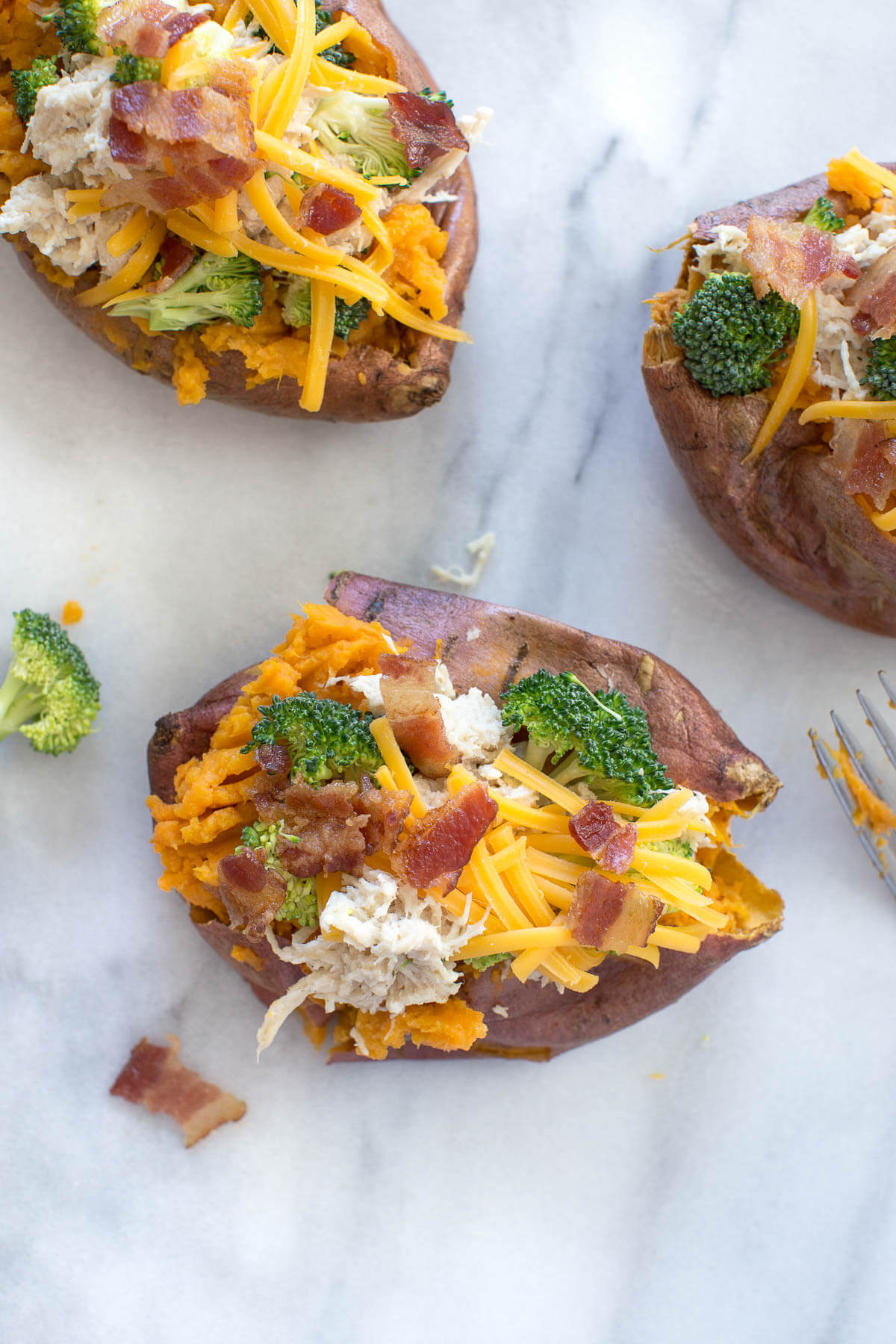 close up of stuffed sweet potatoes with crack chicken, broccoli, bacon and shredded cheese