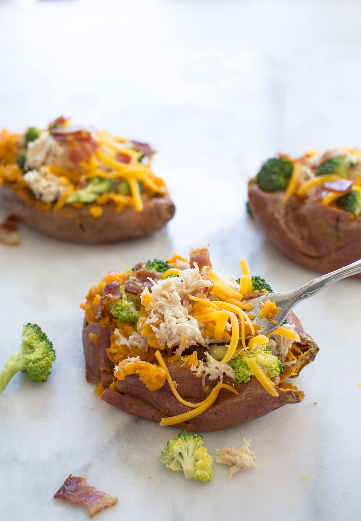 side shot of fork in stuffed sweet potato with crack chicken and broccoli