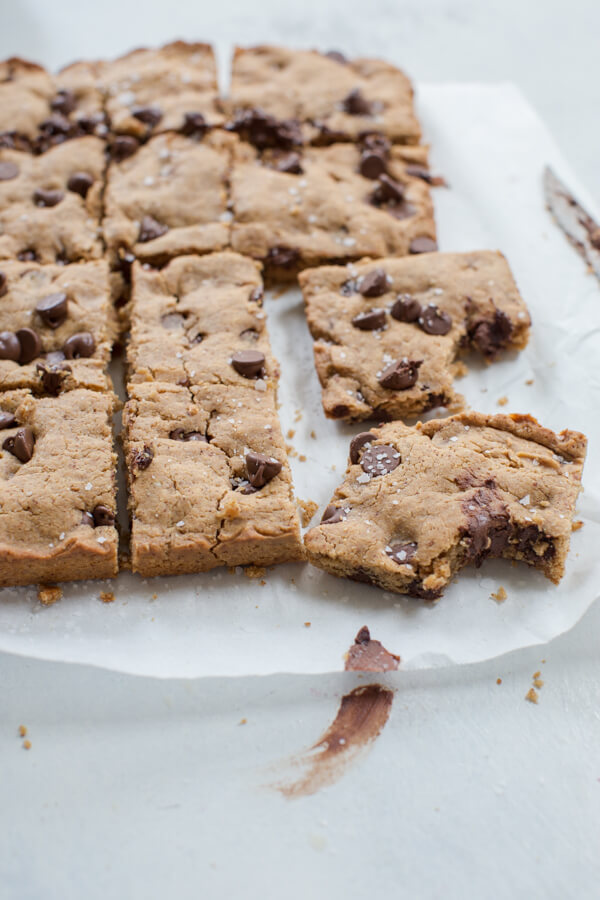 Side shot of two bitten almond butter blondies with melted chocolate and sprinkled with sea salt 