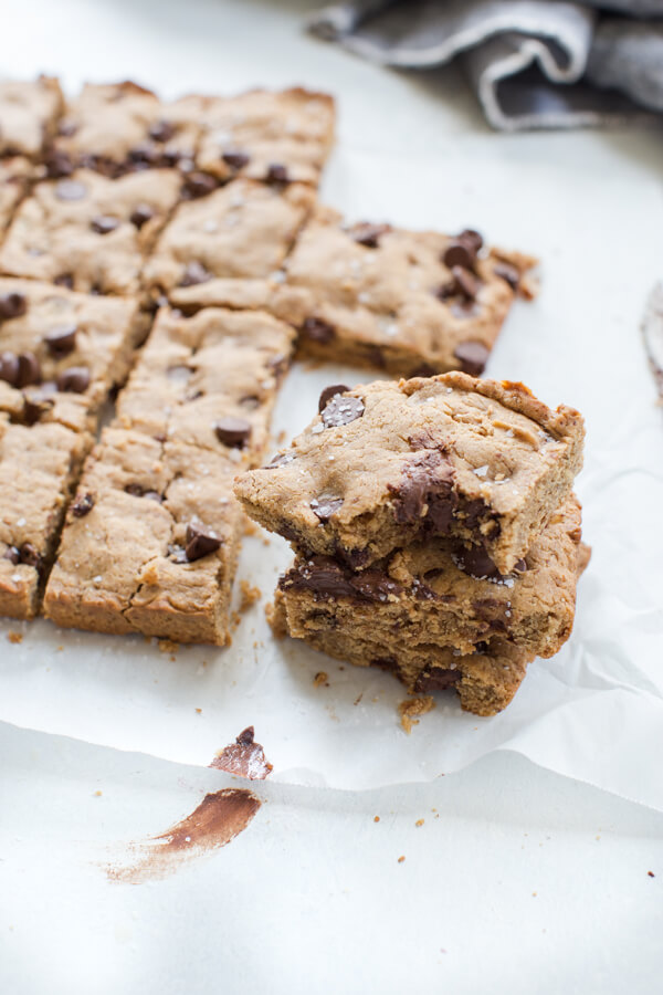 Up close side shot of two stacked almond butter blondies with a gooey chocolatey center